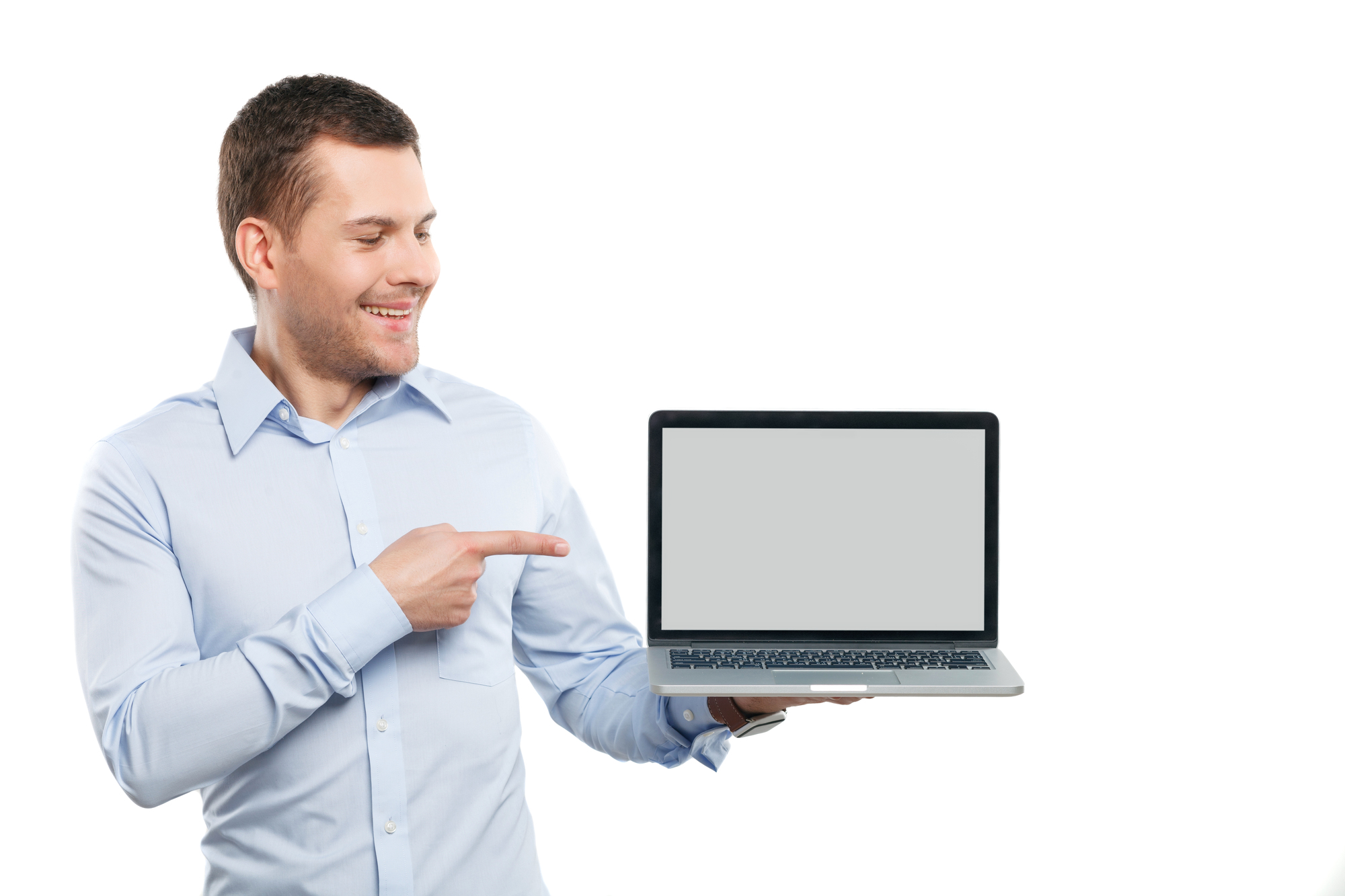 Waist up portrait of handsome businessman holding a modern computer. He is standing and pointing finger at it. The guy is smiling. Isolated